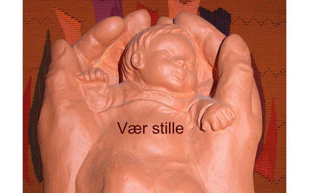 Et barn ligger og sover i Guds hender. Keramikkfigur.